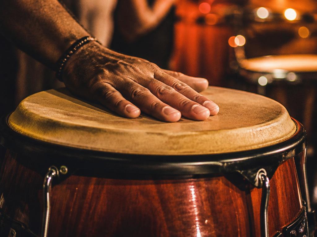 Close up of a hand playing a conga drum under warm stage lighting